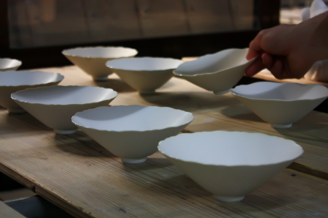 White bowls lined up on wooden boards in the workshop