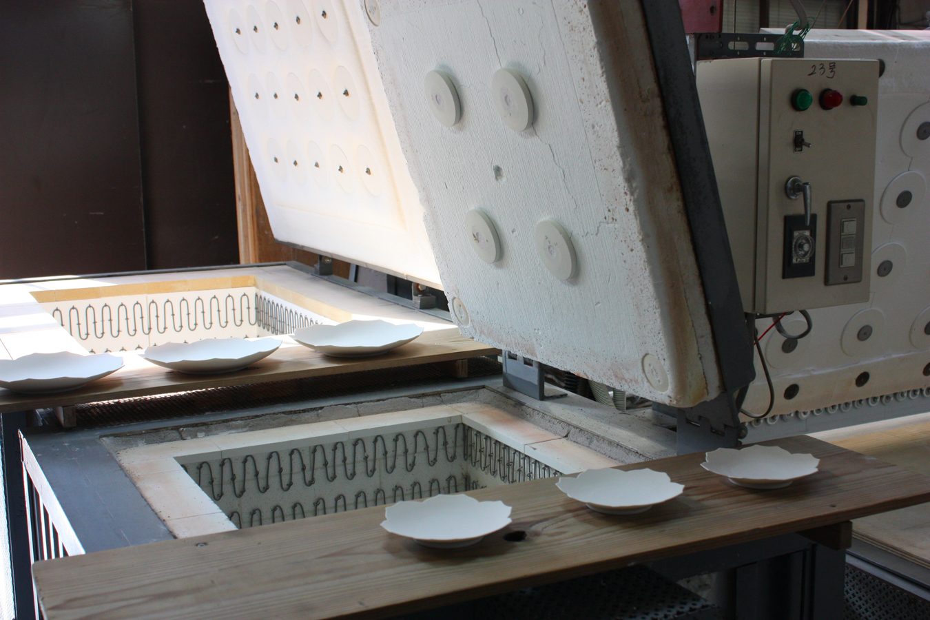 The kiln opened, with white plates ready to fire