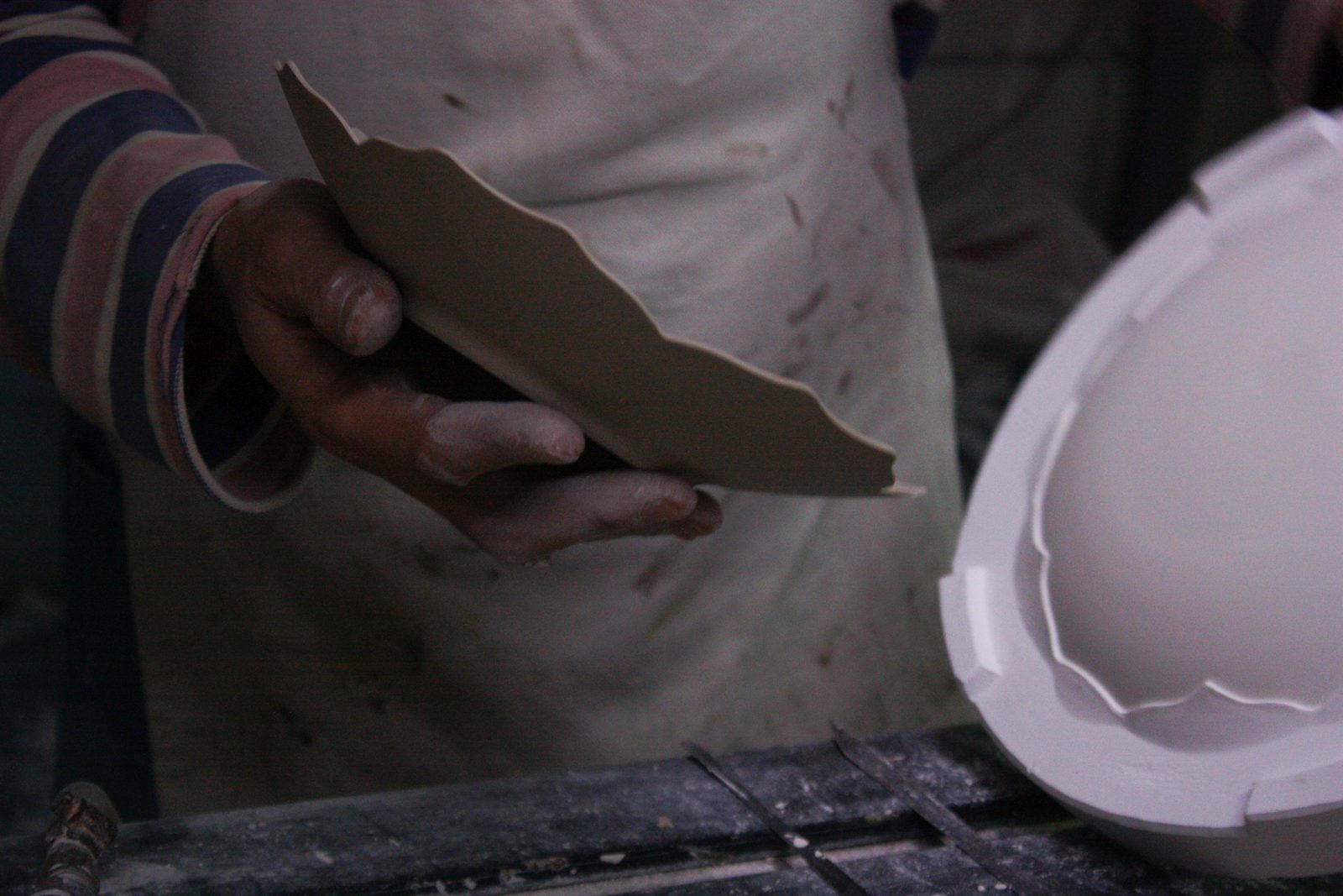 An unfired plate held by its rim