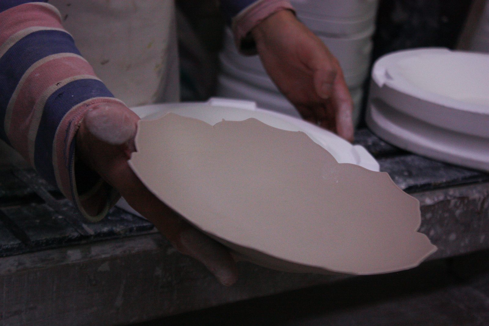 A hand lifting an unfired plate
