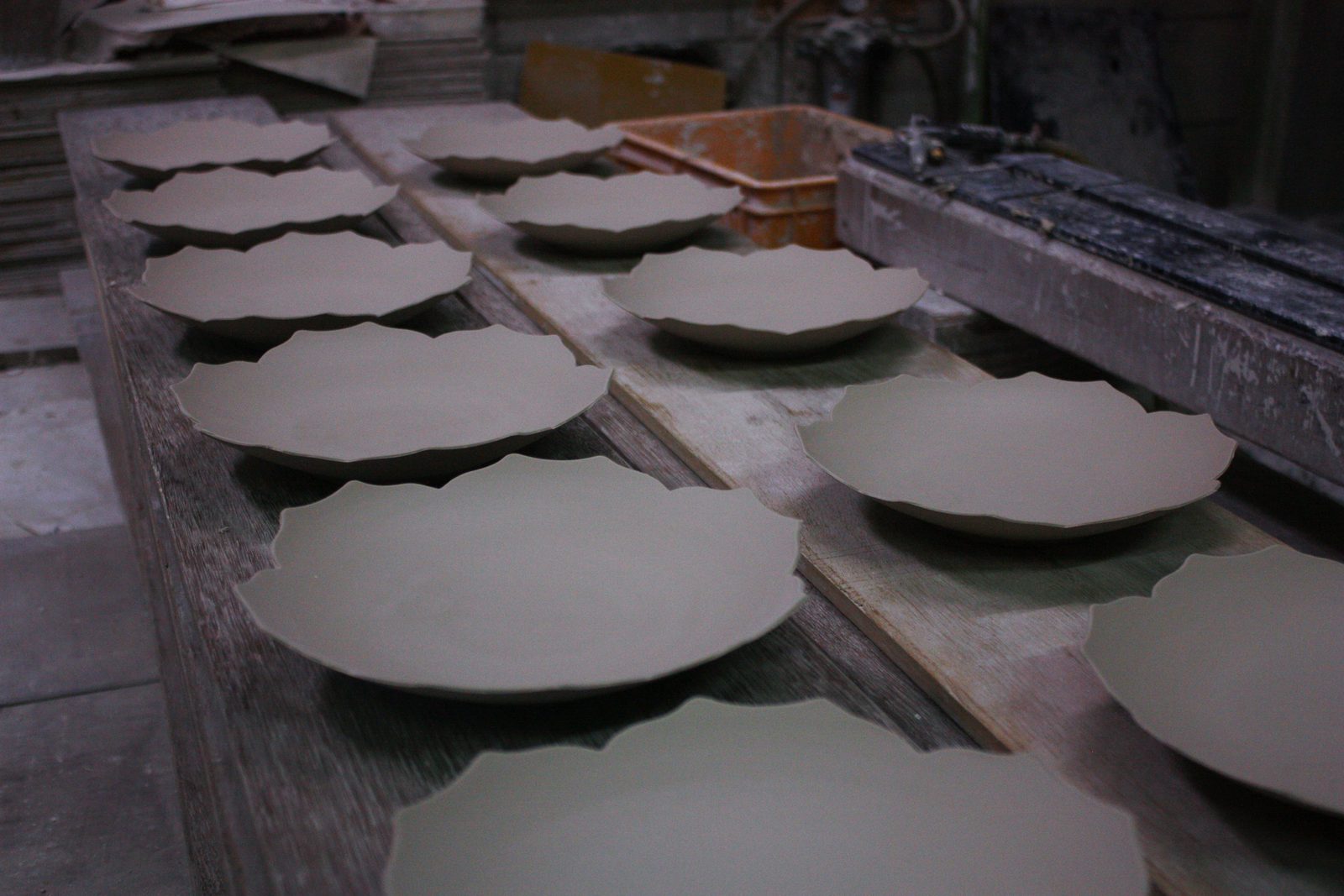 Unfired plates drying on wooden boards